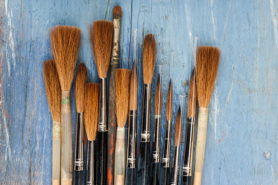  small Clean and new paint brushes on blue wood background