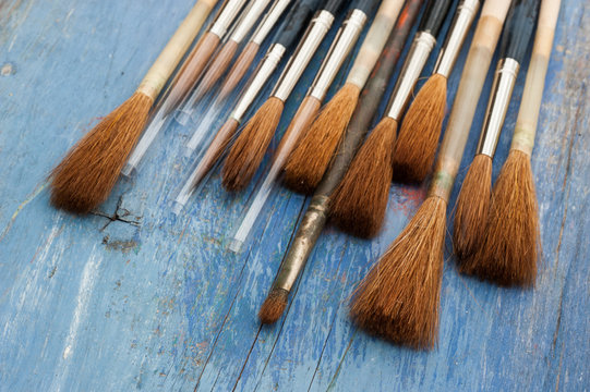 small new paint brushes on blue wood background