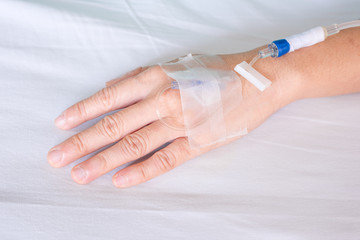 Hand of woman with drip in hospital bed