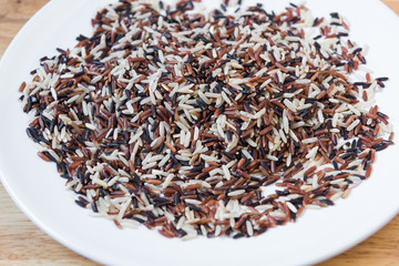 Rice brown  in a ceramic plate with wooden background.