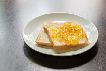 Bread with orange jam on wooden table