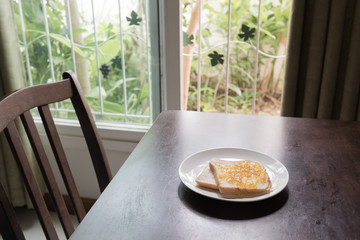 Bread with orange jam on wooden table