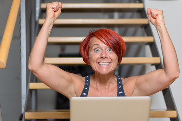 Glückliche Frau Jubelt vor ihrem Laptop