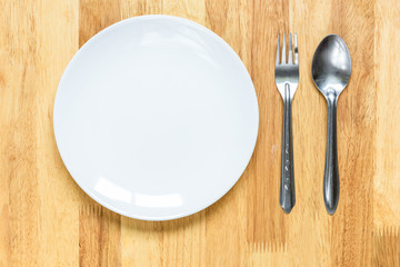plate with spoon and fork on wooden table