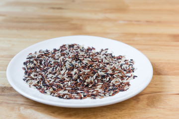 Rice brown  in a ceramic plate with wooden background.