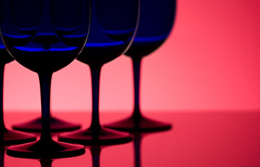 Blue glasses back lit on red background with shallow depth of field