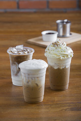 Ice coffee with whipped cream and coffee beans on wooden table.