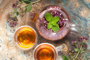 Herbal tea with mint and oregano flowers on metal background