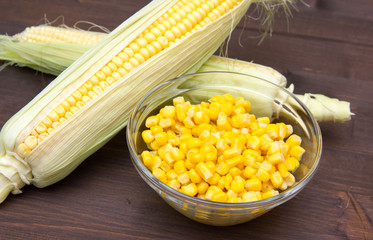 Corn on the cob and bowl on wooden table