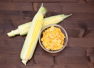 Grains of corn on bowl on wooden table seen from above