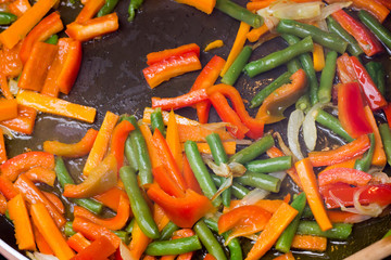 Vegetables cut into strips sauteed with oil seen from above