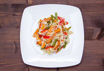 Rice with sauteed vegetables on wooden table seen from above