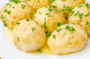 Traditional Ukrainian food boiled new potatoes with butter and dill on wooden table