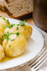 Traditional Ukrainian food boiled new potatoes with butter and dill on wooden table