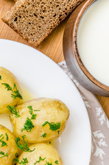 Traditional Ukrainian food boiled new potatoes with butter and dill on wooden table