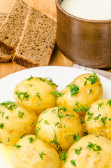 Traditional Ukrainian food boiled new potatoes with butter and dill on wooden table