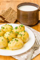 Traditional Ukrainian food boiled new potatoes with butter and dill on wooden table