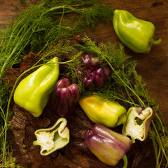 purple and green pepper with dill on a wooden background