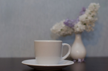 Obraz na płótnie Canvas cup of tea and lilacs in a vase