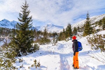 Fototapeta premium Young woman backpacker tourist on hiking trail in winter landscape of Gasienicowa valley, Tatra Mountains, Poland