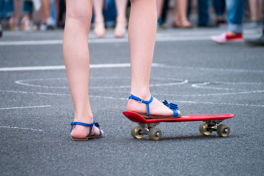 Young girl starts to drive on skateboard in the shadow. Outdoors