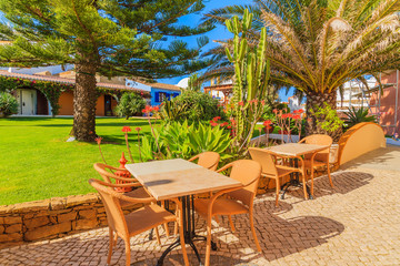Tables with chairs in green park area of Luz town, seaside resort in coast of Algarve region, Portugal