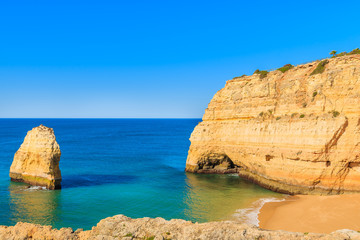 Fototapeta premium View of sandy beach and rock cliffs near Carvoeiro town, Algarve, Portugal