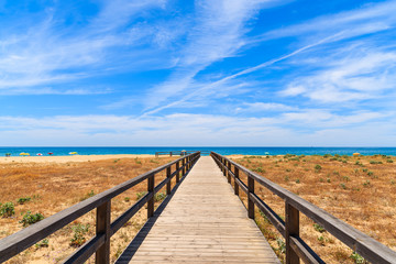 Walkway to sandy beach in Armacao de Pera coastal town, Algarve region, Portugal