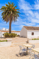 Church with palm tree on coastal promenade in seaside town of Armacao de Pera, Portugal
