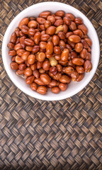 Deep fried peanuts in white bowl over rustic wicker background