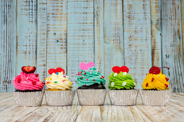 Fototapeta premium Colorful cupcakes on a wooden background