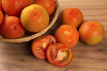 Some tomatoes over a wooden surface on a tomato field as backgro