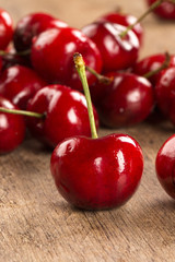 A wooden pot full of cherries over a wooden surface