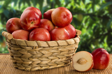 Some peaches in a basket over a wooden surface on a green and na