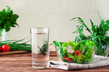 glass of clean water with a salad of fresh vegetables in the rustic kitchen. The concept of healthy lifestyle and diet. Close-up. Copy space. Free space for text