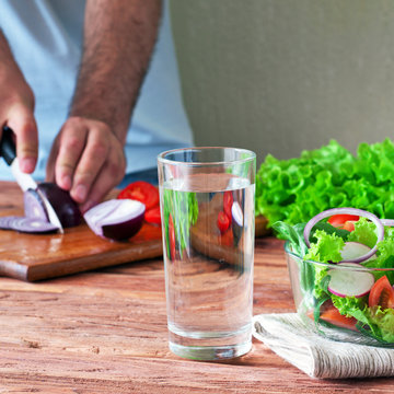 glass of clean water with a salad of fresh vegetables in the rustic kitchen. The concept of healthy lifestyle and diet. Close-up. Copy space. Free space for text