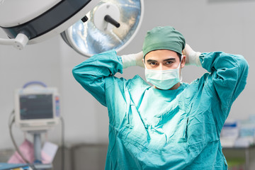 Obraz na płótnie Canvas Male surgeon tying mask at operating room