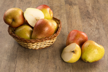 Some pears in a basket over a wooden surface seen from above