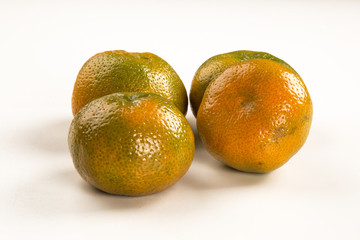 Some tangerines in a basket over a wooden surface