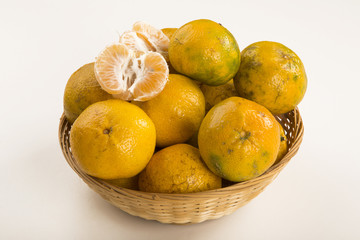 Some tangerines in a basket over a wooden surface