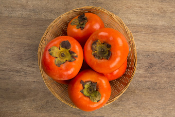 Some khaki fruits over a wooden surface