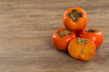 Some khaki fruits over a wooden surface