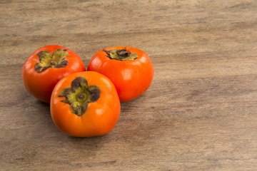 Some khaki fruits over a wooden surface