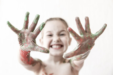 Little girl showing her hands, covered in finger paint