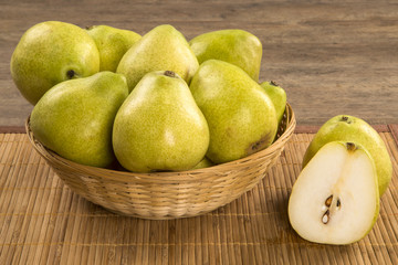 Some pears in a basket over a wooden surface seen from above