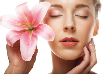 Beauty face of the young woman with pink lily 