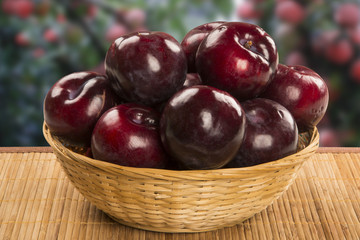 Fresh bright plums in the bowl on board