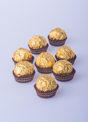 Chocolate ball in a gold foil paper on a background.