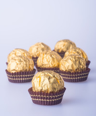 Chocolate ball in a gold foil paper on a background.