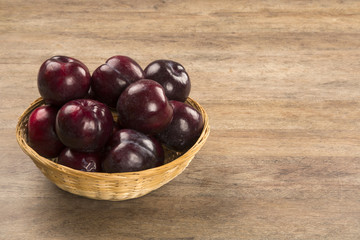 Fresh bright plums in the bowl on board